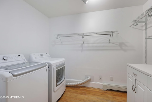 washroom with a baseboard heating unit, cabinet space, light wood-style floors, and washer and clothes dryer