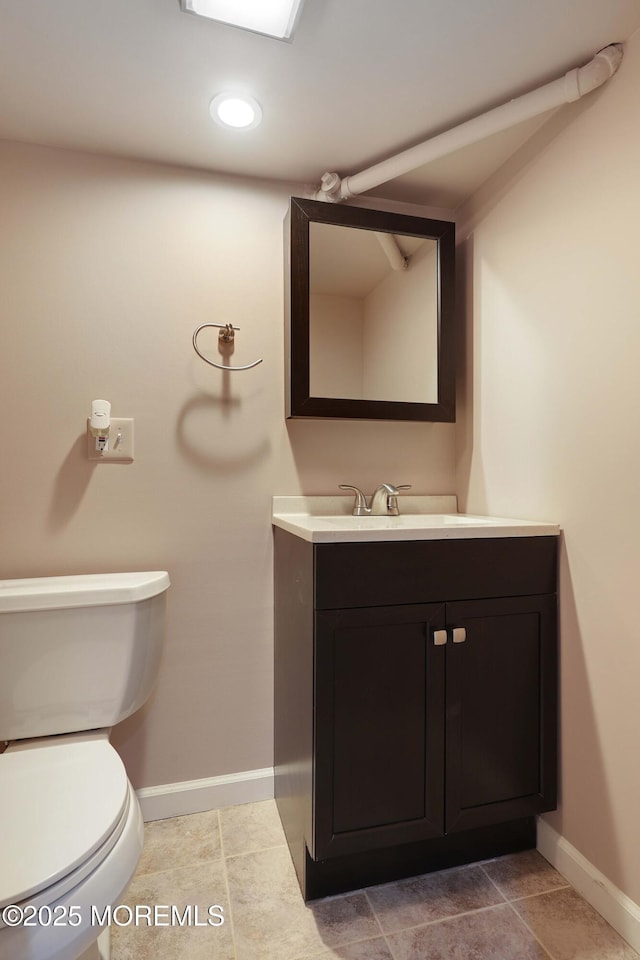 half bathroom with recessed lighting, baseboards, toilet, and vanity