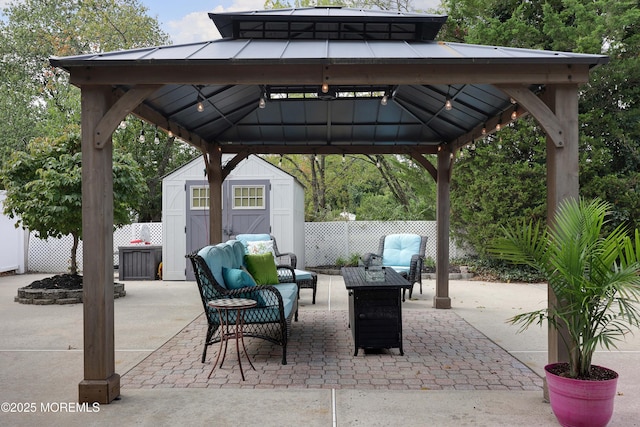 view of patio with a storage unit, an outbuilding, fence, a gazebo, and an outdoor living space with a fire pit