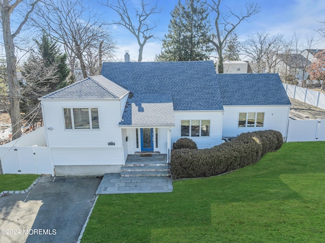 view of front of house featuring a gate, roof with shingles, a fenced backyard, a chimney, and a front lawn