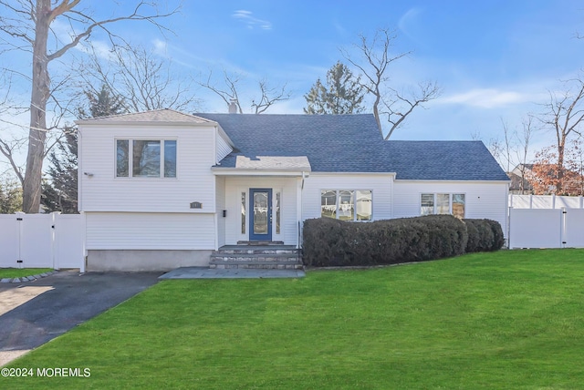 view of front facade featuring driveway, fence, a front yard, and a gate