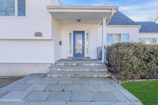 view of exterior entry featuring roof with shingles