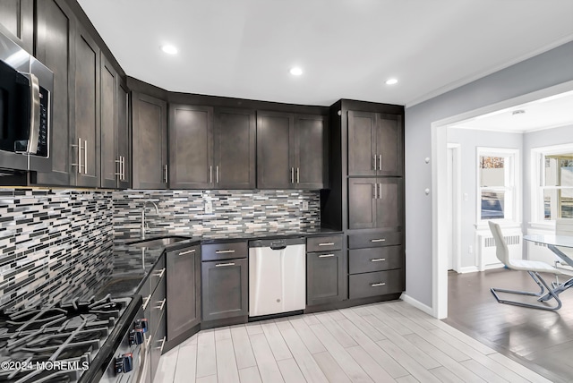 kitchen with radiator heating unit, a sink, stainless steel appliances, dark brown cabinets, and tasteful backsplash