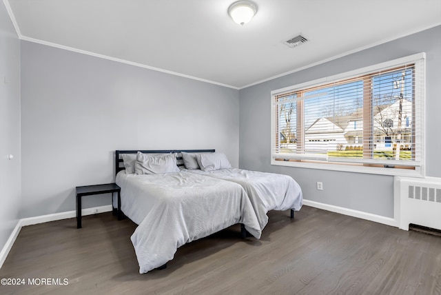 bedroom with visible vents, wood finished floors, radiator heating unit, crown molding, and baseboards