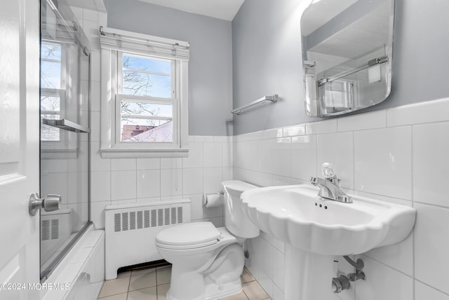 full bathroom with toilet, tile patterned floors, radiator heating unit, and tile walls