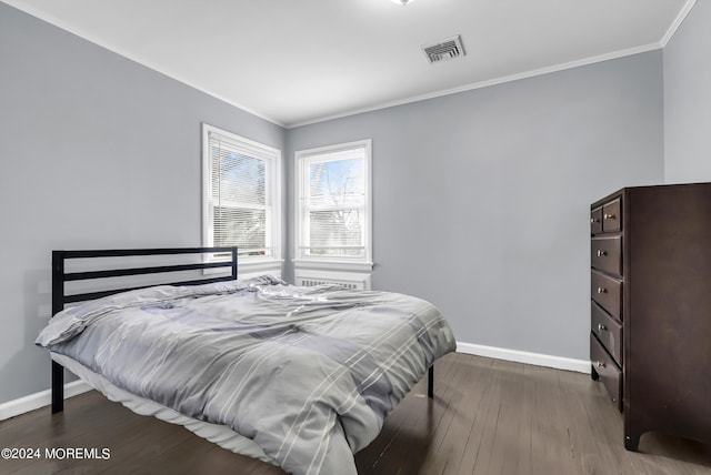 bedroom featuring wood finished floors, crown molding, visible vents, and baseboards