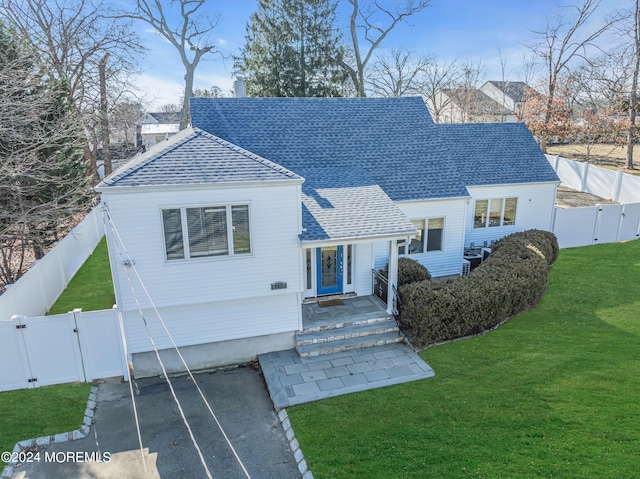 view of front facade featuring a front lawn, a gate, a fenced backyard, and driveway