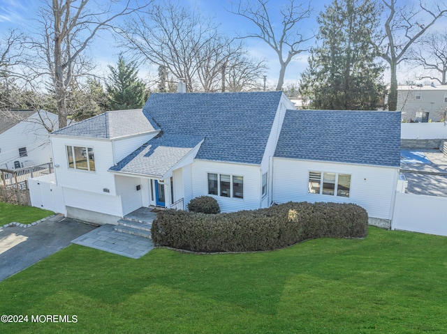 view of front of house featuring fence, roof with shingles, a front lawn, a garage, and aphalt driveway