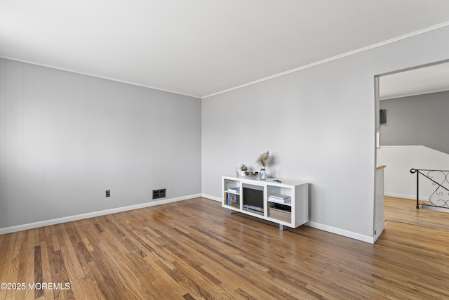 unfurnished room featuring baseboards, wood finished floors, visible vents, and ornamental molding