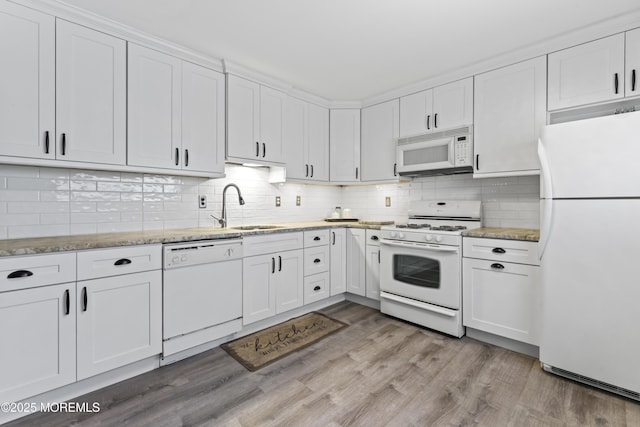 kitchen with a sink, white appliances, light wood-style floors, and white cabinetry