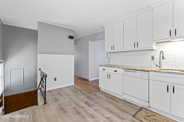 kitchen with light wood finished floors, ornamental molding, a sink, white cabinets, and dishwasher