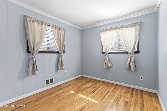 unfurnished room with visible vents, crown molding, baseboards, and hardwood / wood-style flooring