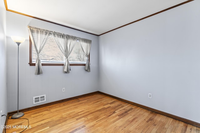 spare room featuring visible vents, baseboards, light wood-style flooring, and ornamental molding