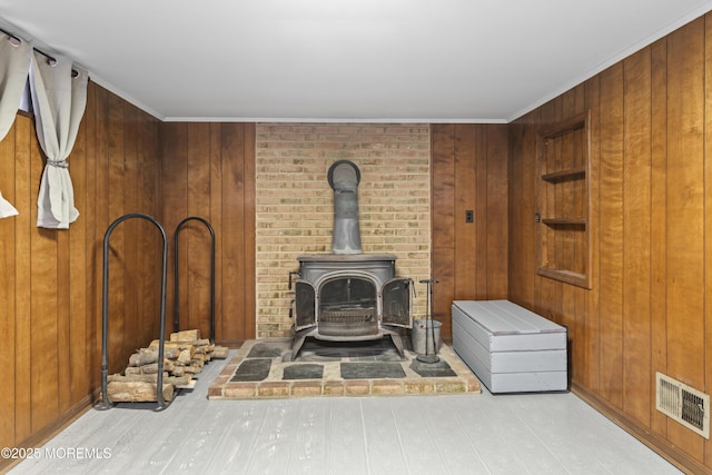 interior details with visible vents, a wood stove, wooden walls, and wood finished floors