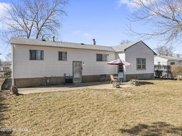 back of property featuring a lawn, a shingled roof, central AC unit, a chimney, and a patio area