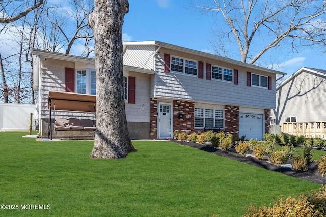 tri-level home featuring brick siding, a garage, a front yard, and fence