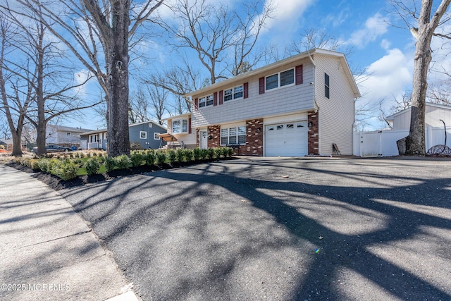 view of front of property featuring a garage, brick siding, and fence