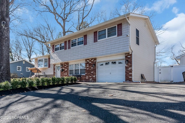 tri-level home featuring brick siding, aphalt driveway, and a garage