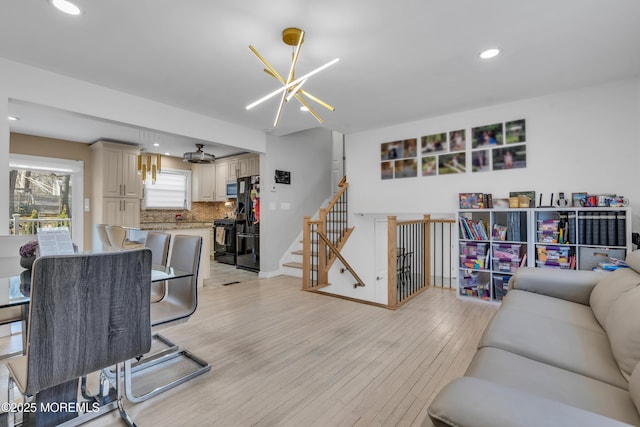 living room featuring baseboards, a chandelier, stairs, light wood-type flooring, and recessed lighting