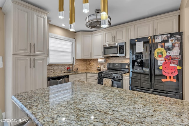 kitchen featuring tasteful backsplash, black appliances, light stone counters, and a sink