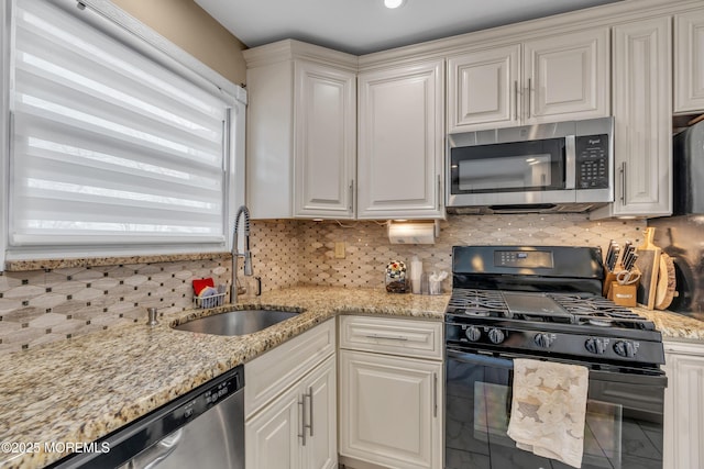 kitchen featuring a sink, decorative backsplash, appliances with stainless steel finishes, and white cabinets