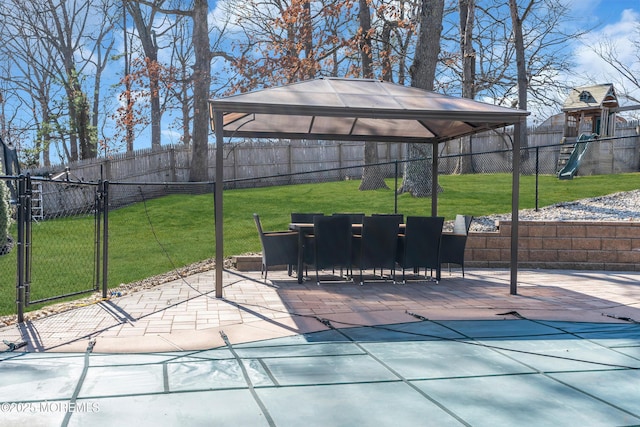 view of patio / terrace with outdoor dining space, a playground, a gate, and a fenced backyard