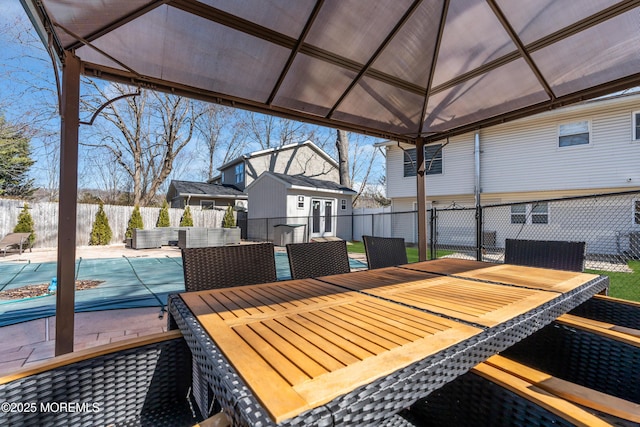 wooden deck with an outbuilding, a fenced in pool, outdoor dining area, and a fenced backyard