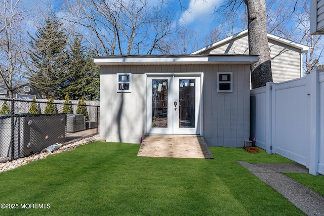 back of house with an outbuilding, central air condition unit, a yard, and a fenced backyard