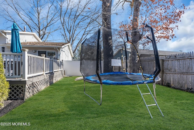 view of yard featuring a fenced backyard, a wooden deck, and a trampoline