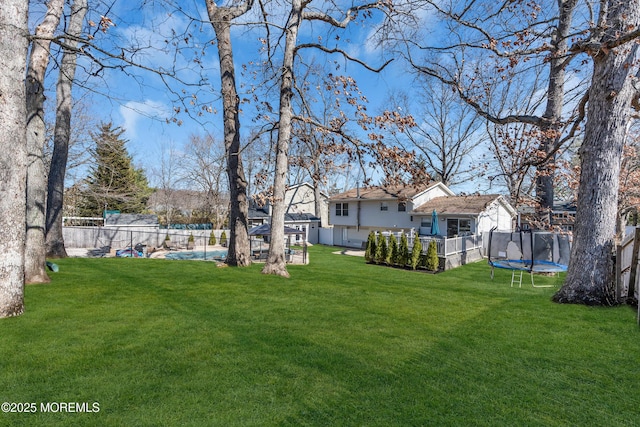 view of yard featuring a trampoline and a fenced backyard