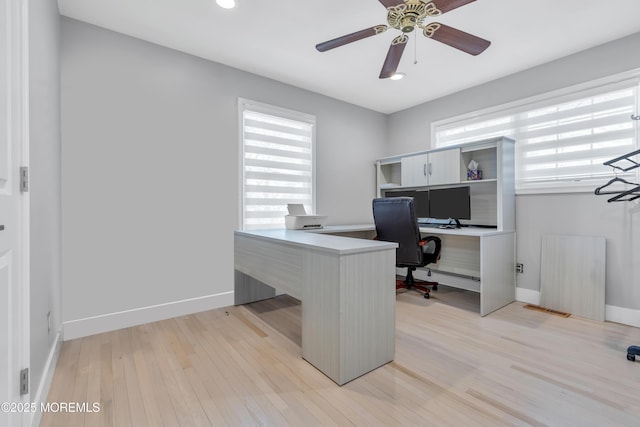 home office with visible vents, baseboards, light wood-style floors, and ceiling fan