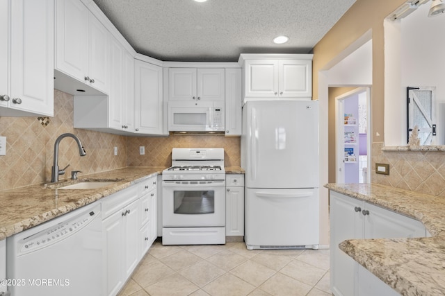 kitchen with white appliances, white cabinets, light tile patterned flooring, and a sink