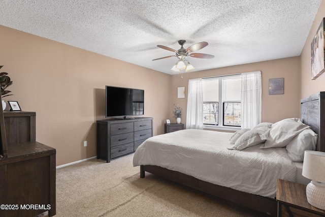 bedroom with a textured ceiling, light colored carpet, baseboards, and ceiling fan