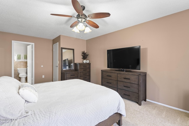 bedroom with baseboards, ensuite bath, ceiling fan, a textured ceiling, and light carpet