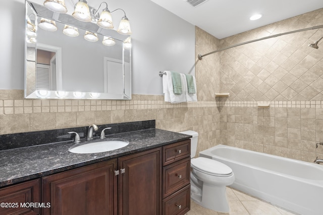 bathroom with tile patterned floors, toilet, shower / tub combination, tile walls, and vanity