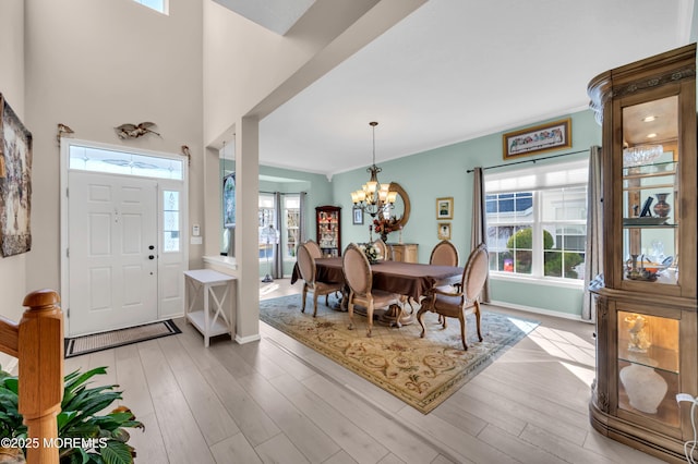 foyer entrance featuring a notable chandelier, light wood-style flooring, and baseboards