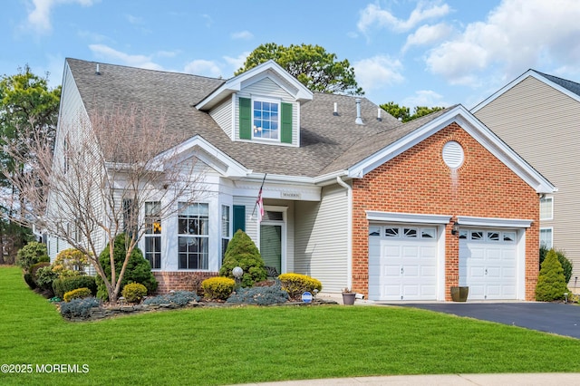 view of front facade with a front yard, driveway, roof with shingles, an attached garage, and brick siding