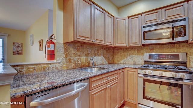 kitchen with decorative backsplash, appliances with stainless steel finishes, stone countertops, and a sink