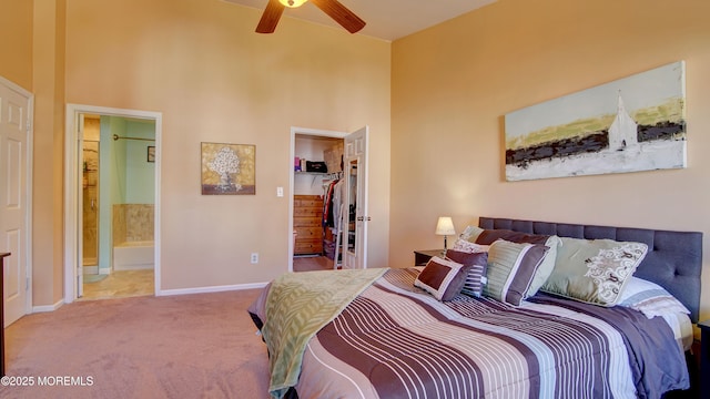 carpeted bedroom with connected bathroom, a walk in closet, baseboards, a high ceiling, and a closet