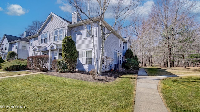 view of side of property with a lawn, central AC unit, and a chimney