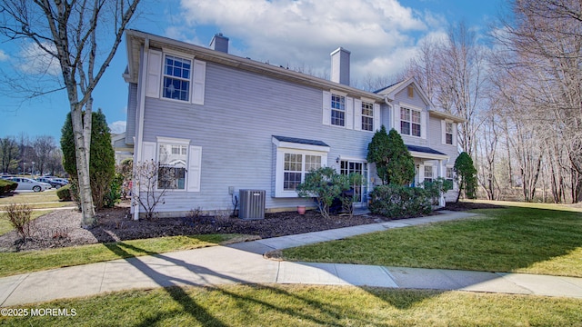 view of front of house with a front yard, central AC, and a chimney