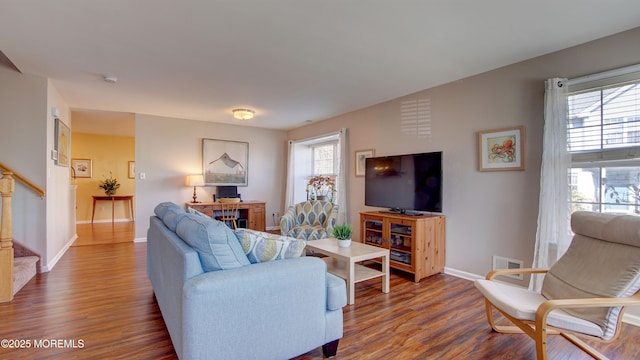 living room with stairway, baseboards, visible vents, and wood finished floors