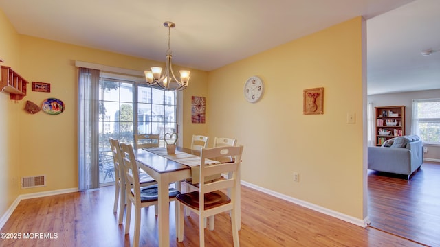 dining room with an inviting chandelier, light wood-style floors, visible vents, and baseboards