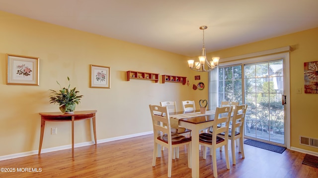 dining space featuring visible vents, baseboards, light wood-type flooring, and an inviting chandelier