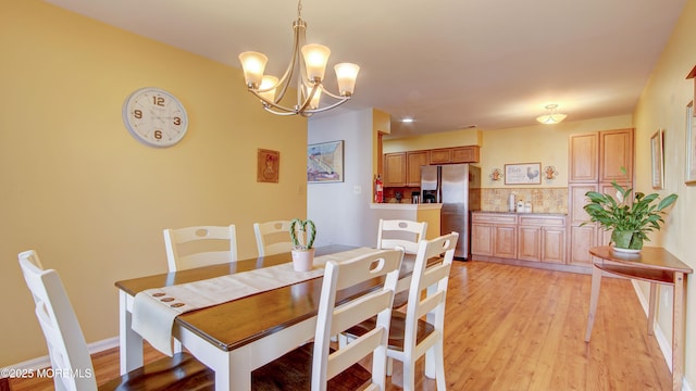 dining area with light wood-type flooring and a chandelier