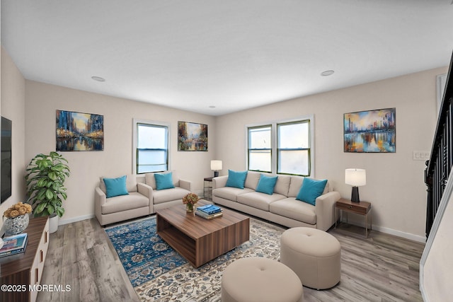 living room featuring baseboards, a healthy amount of sunlight, and light wood-style flooring