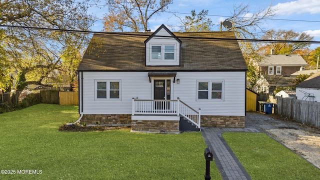 dutch colonial featuring a shingled roof, a front yard, and fence