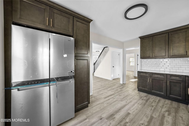 kitchen featuring dark brown cabinetry, light wood-style flooring, and freestanding refrigerator