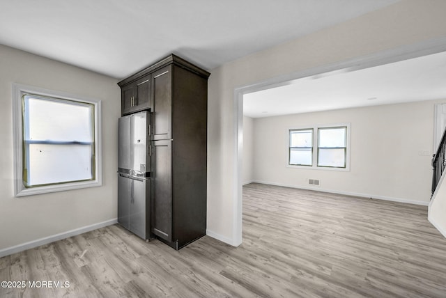 kitchen with visible vents, dark brown cabinets, baseboards, freestanding refrigerator, and light wood-style floors