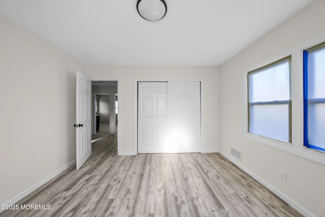 unfurnished bedroom with visible vents, baseboards, a closet, and wood finished floors